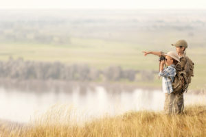Kinder auf Safari in Simbabwe schauen in die Ferne auf einer Berg-Kuppe auf einen See